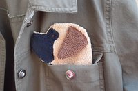 Dog shaped cloth peeking out of a jean jacket pocket.