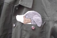 Dog shaped cloth peeking out of a jean jacket pocket.