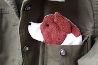 Smudge Dog peeking out of the pocket of a jean jacket.