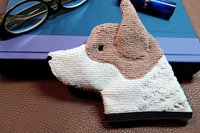 Red Heeler Smudge Dog waiting to be used as a bookmark leaning against a book with glasses and lipstick on top