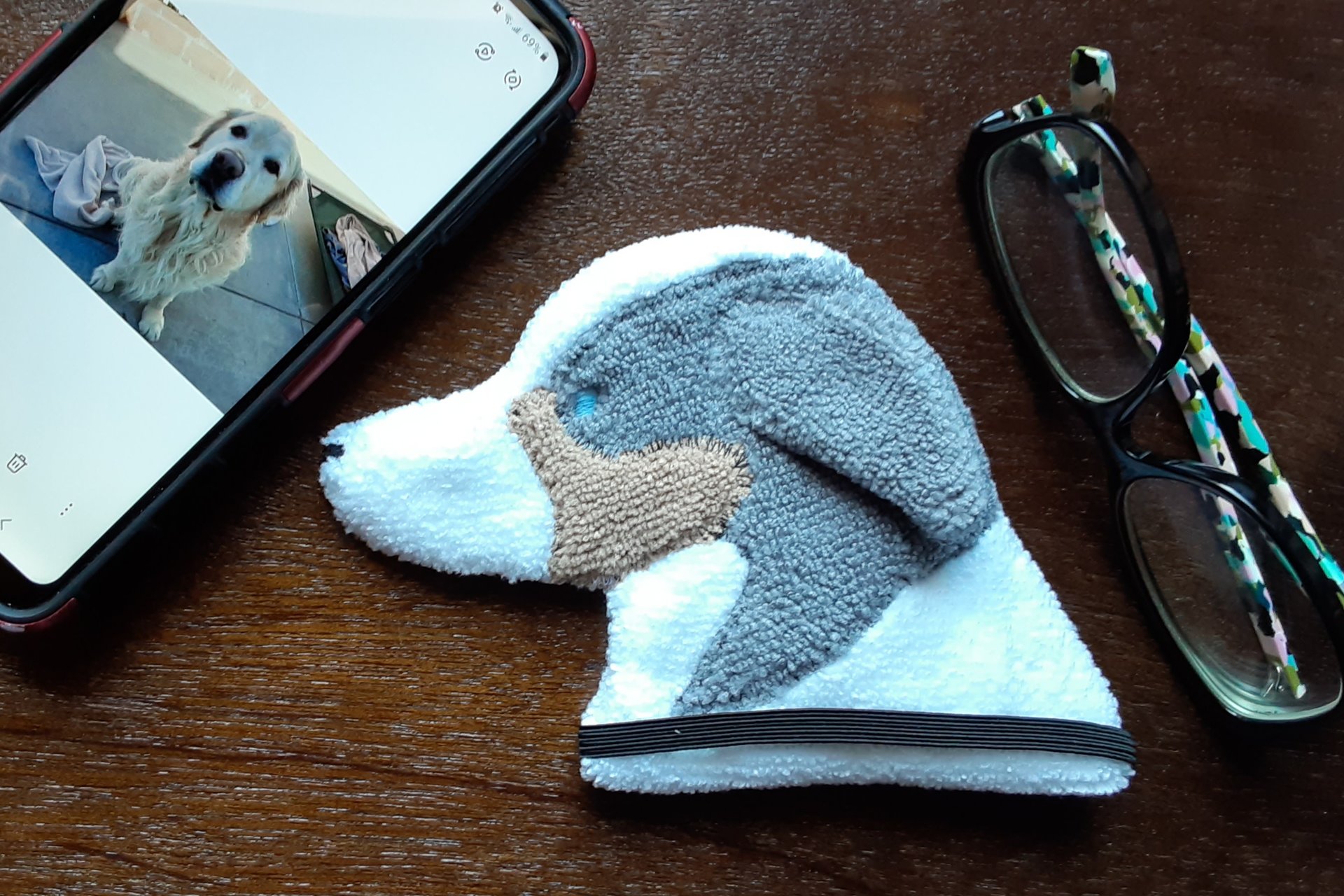 Smudge Dog shown with glasses and phone. Two of the items it can clean.