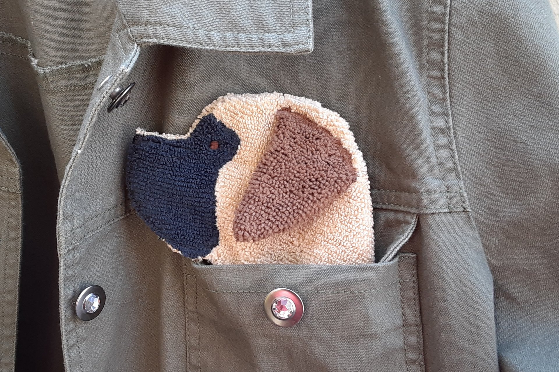 Dog shaped cloth peeking out of a jean jacket pocket.
