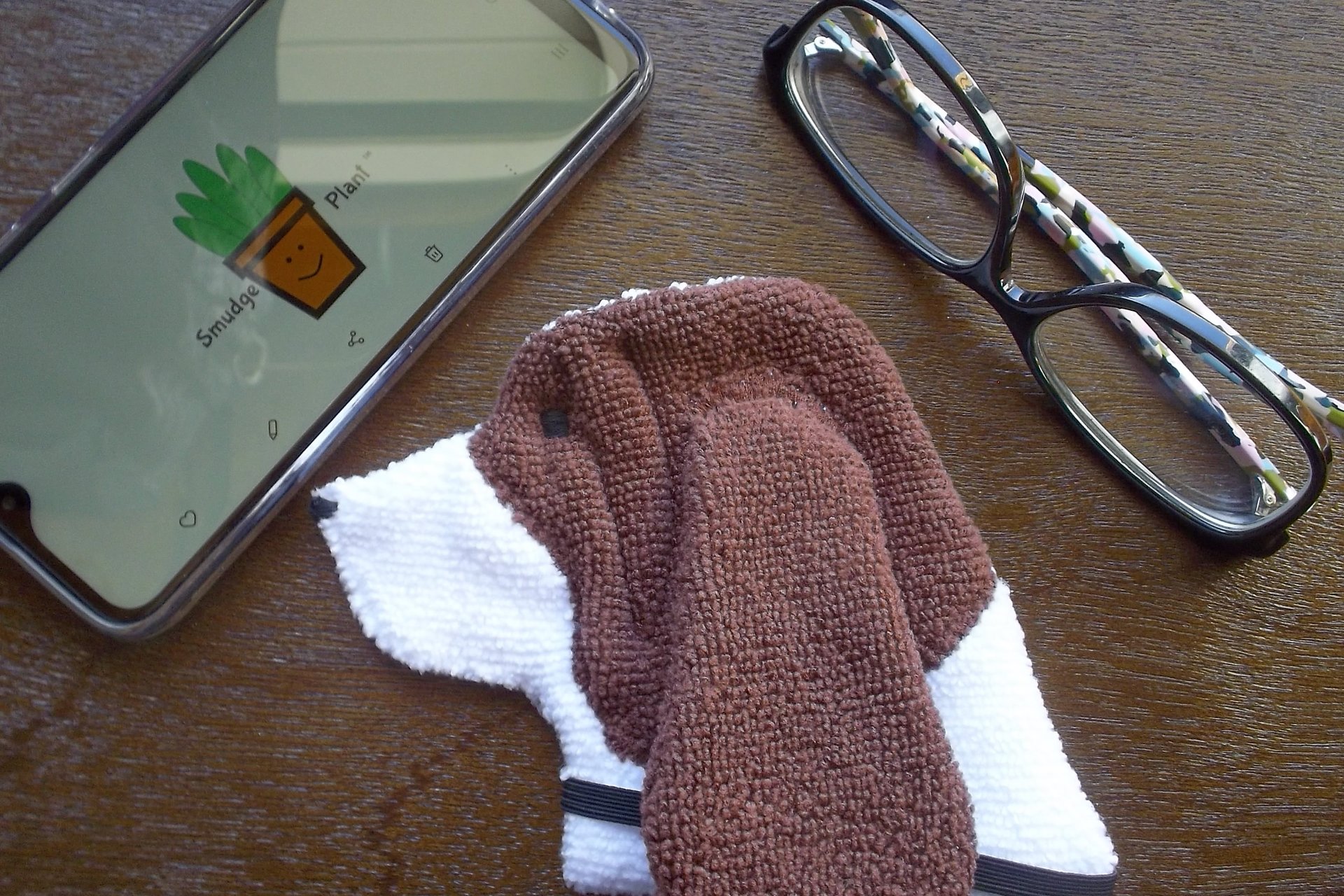 Smudge Dog shown with phone and glasses. Two of the items it can clean.