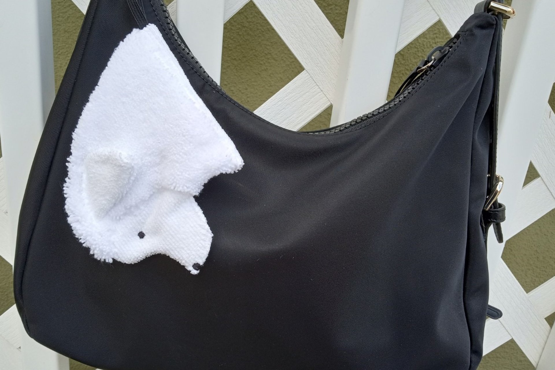 Great Pyrenees Smudge dog with collar looped on handbag.