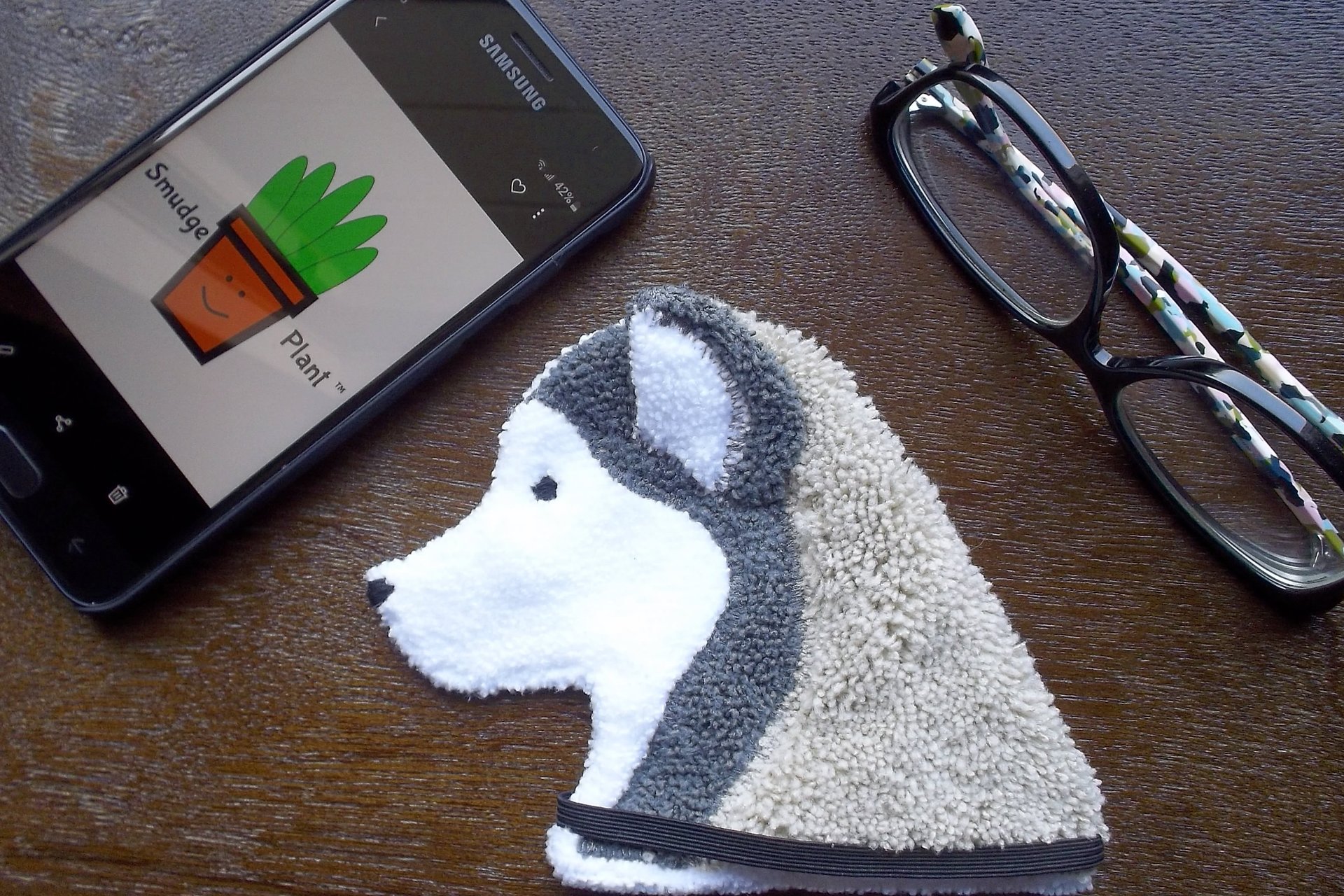 Smudge Dog shown with phone and glasses. Two of the items it can clean.