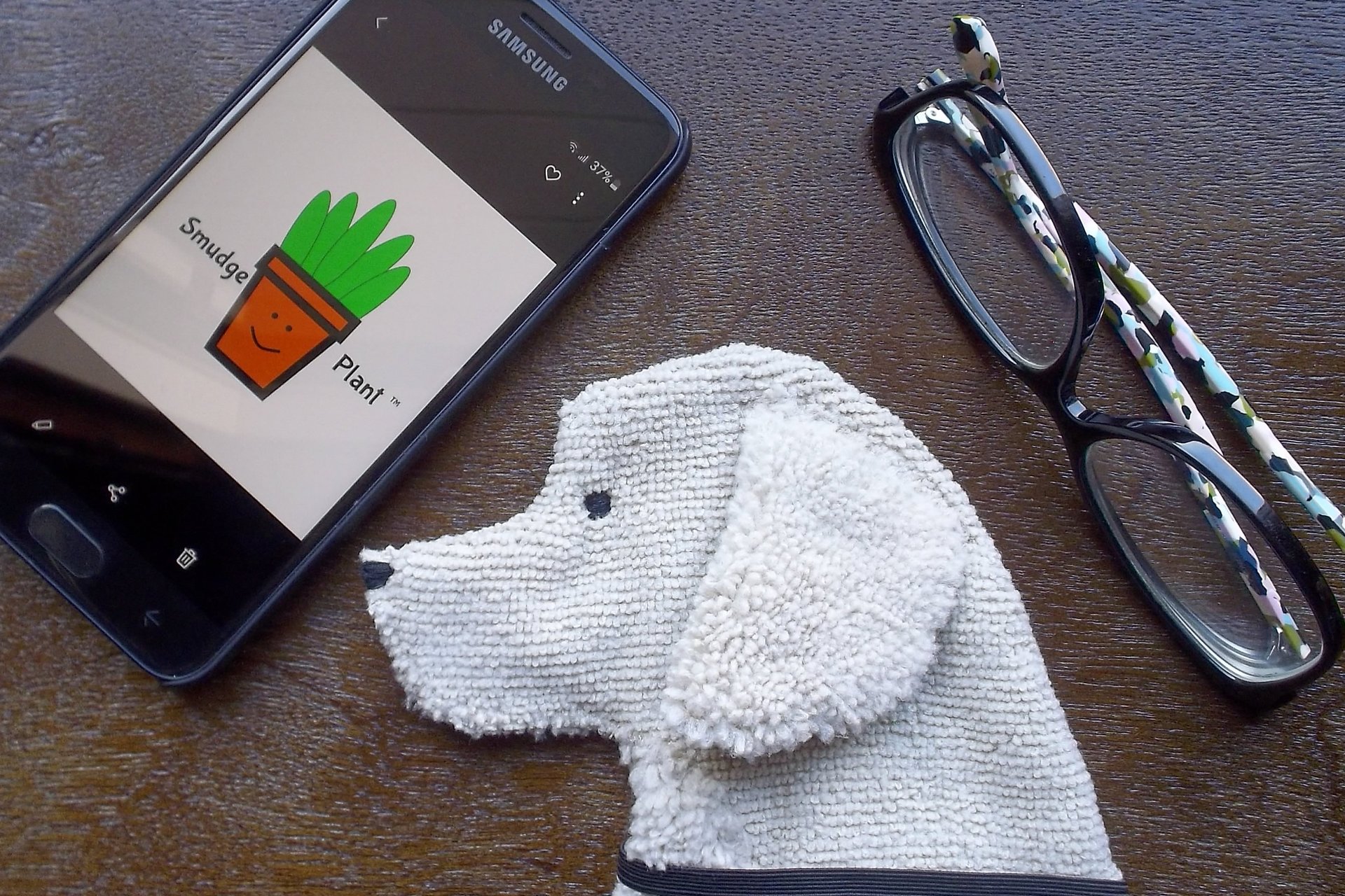 Smudge Dog shown with phone and glasses. Two of the items it can clean.