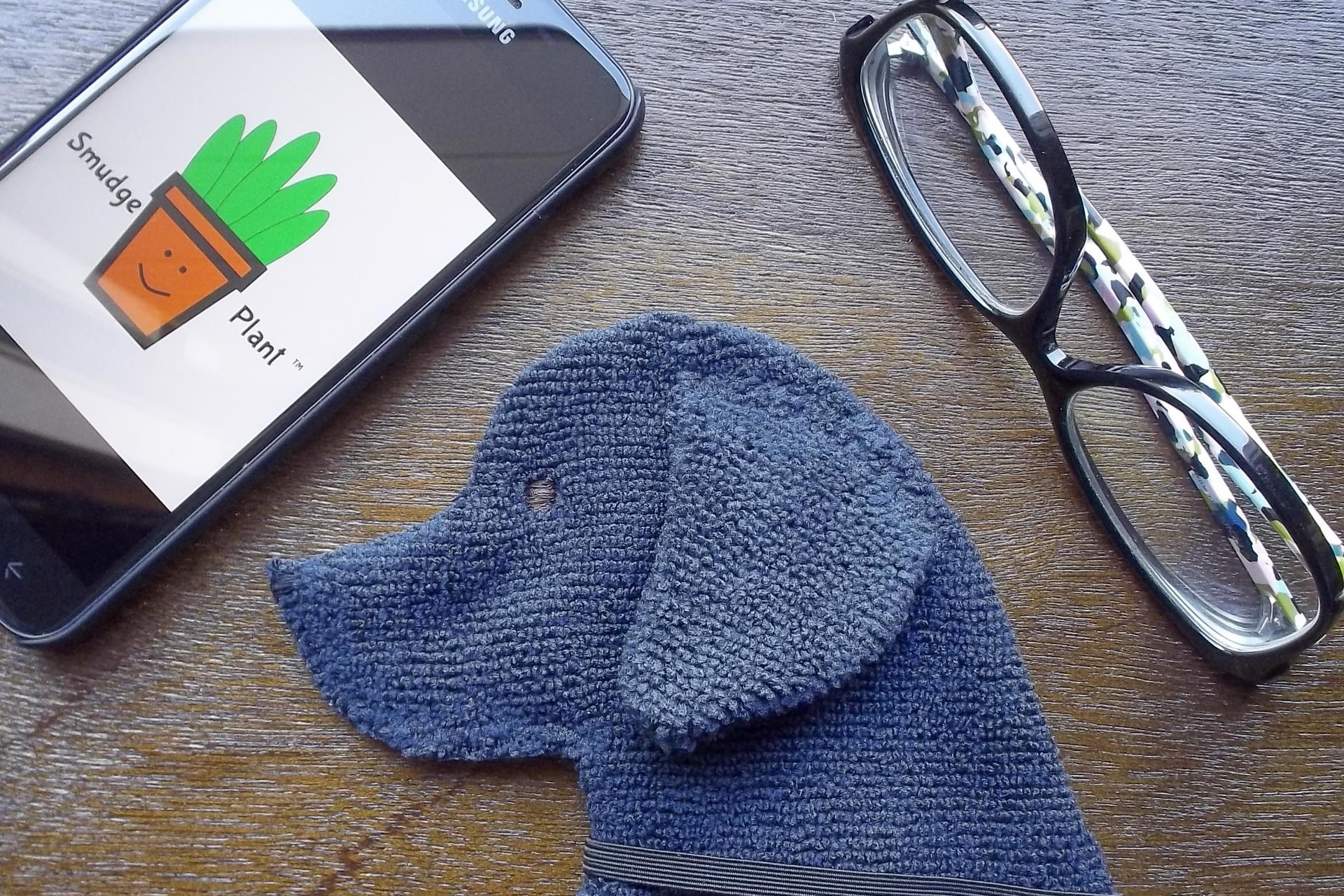 Smudge Dog shown with glasses and phone. Two of the items it can clean.